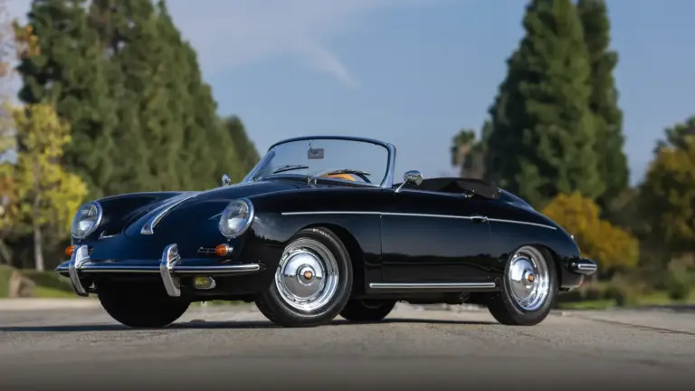 Schwarzer Porsche 356 B Super 90 Roadster von 1960, offen, frontal seitlich aufgenommen, vor unscharfem Grün im Hintergrund.