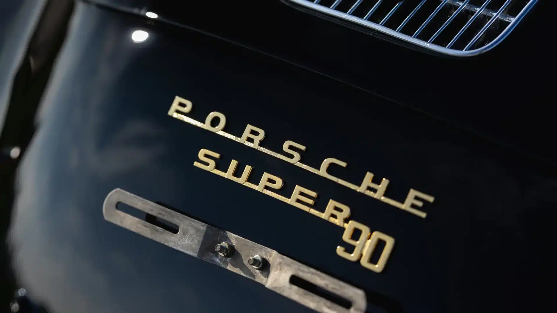 Goldenes Porsche Super 90 Modellschriftzug-Emblem auf schwarzem Porsche 356 B Roadster.