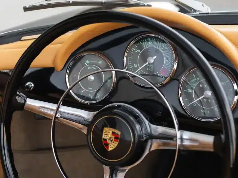 Blick auf das Cockpit eines Porsche 356 B Super 90 Roadster by Drauz mit klassischen Rundinstrumenten und Porsche-Emblem am Lenkrad.