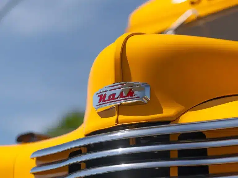Nahaufnahme der Frontpartie mit Nash-Emblem eines gelben historischen Schulbusses Baujahr 1949.