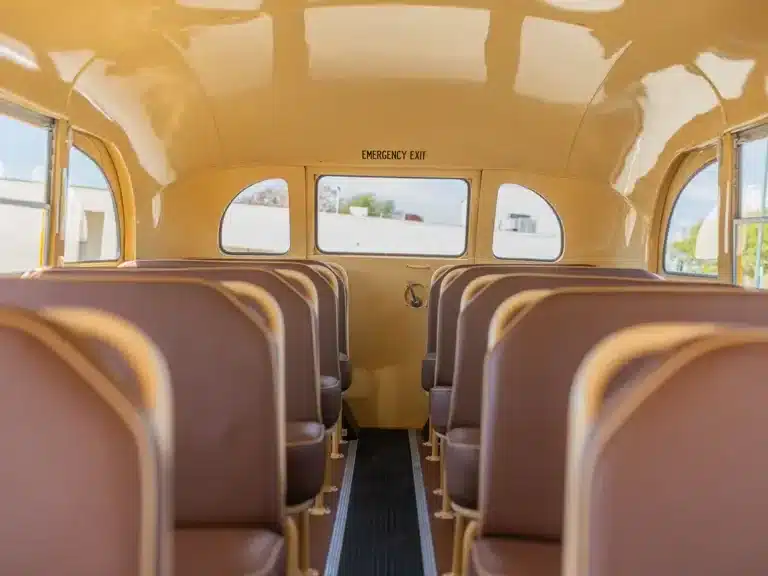 Innenansicht des restaurierten Nash Model 3248 School Bus von 1949 mit braunen Sitzbänken und gelbem Dach