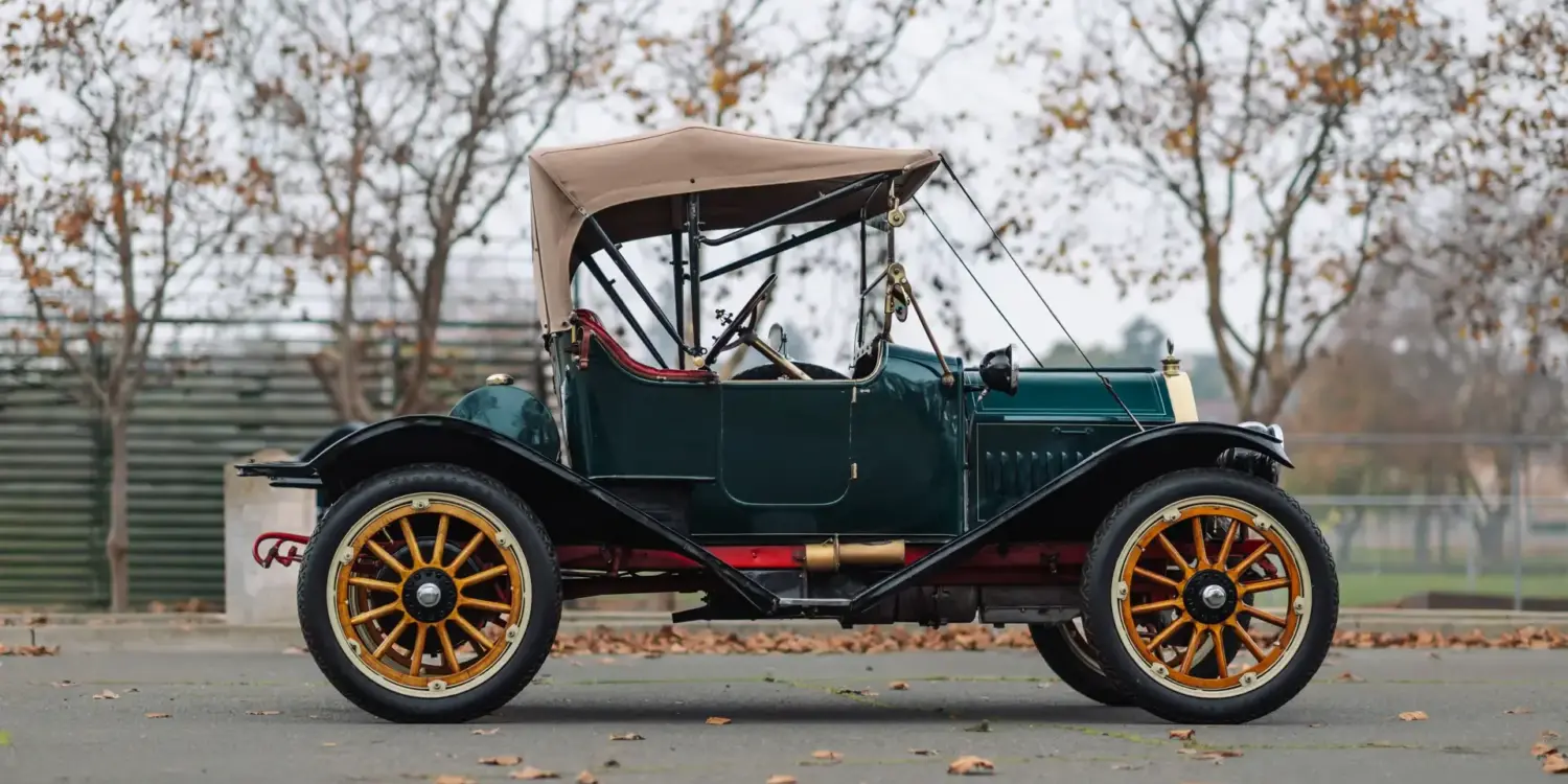 Seitenansicht des Herreshoff Model 30 Runabout von 1913 mit grünem Lack, Holzspeichenrädern, Stoffverdeck und roter Innenausstattung.