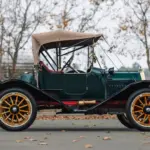 Seitenansicht des Herreshoff Model 30 Runabout von 1913 mit grünem Lack, Holzspeichenrädern, Stoffverdeck und roter Innenausstattung.