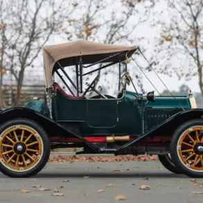 Seitenansicht des Herreshoff Model 30 Runabout von 1913 mit grünem Lack, Holzspeichenrädern, Stoffverdeck und roter Innenausstattung.
