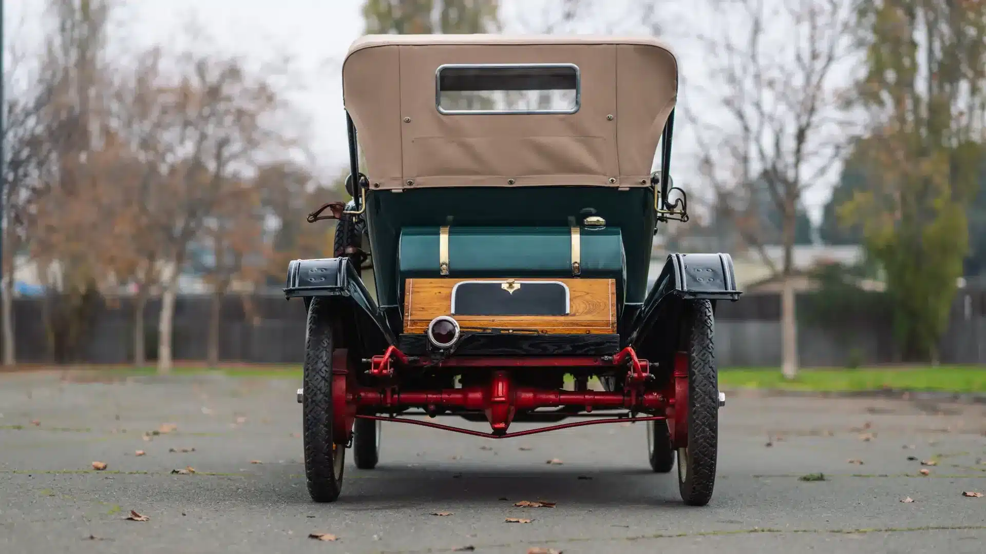 Heckansicht des historischen Herreshoff Model 30 Runabout von 1913 mit grünem Lack, Holzapplikationen und beigem Verdeck.