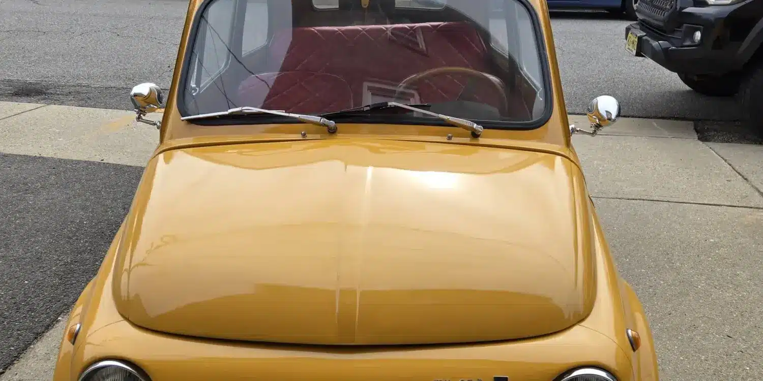 Gelber Fiat 500 Baujahr 1969 aus der Frontperspektive auf einem Bürgersteig geparkt.