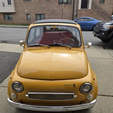 Gelber Fiat 500 Baujahr 1969 aus der Frontperspektive auf einem Bürgersteig geparkt.