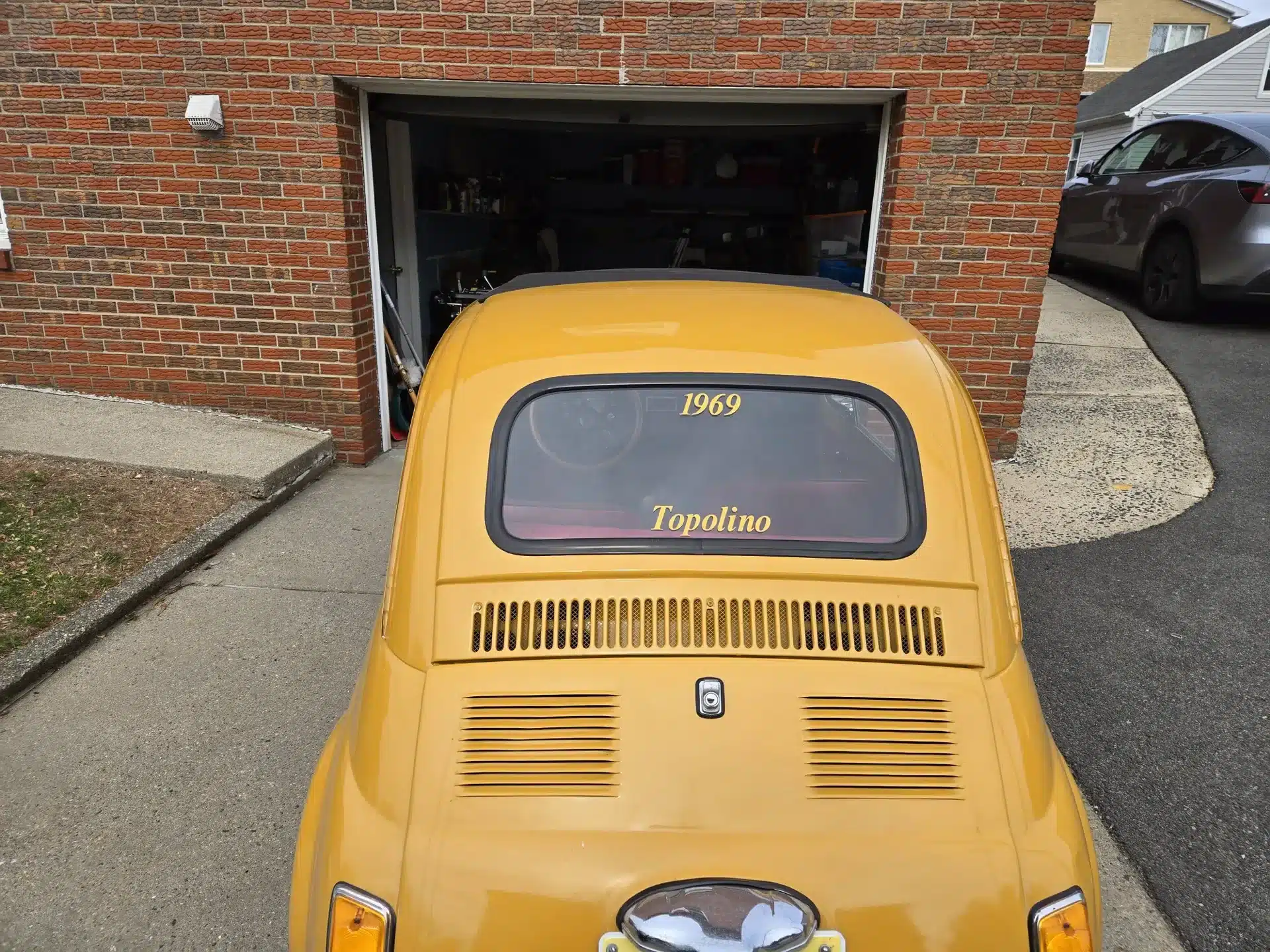 Gelber Fiat 500 Baujahr 1969 von hinten vor einer Garage geparkt
