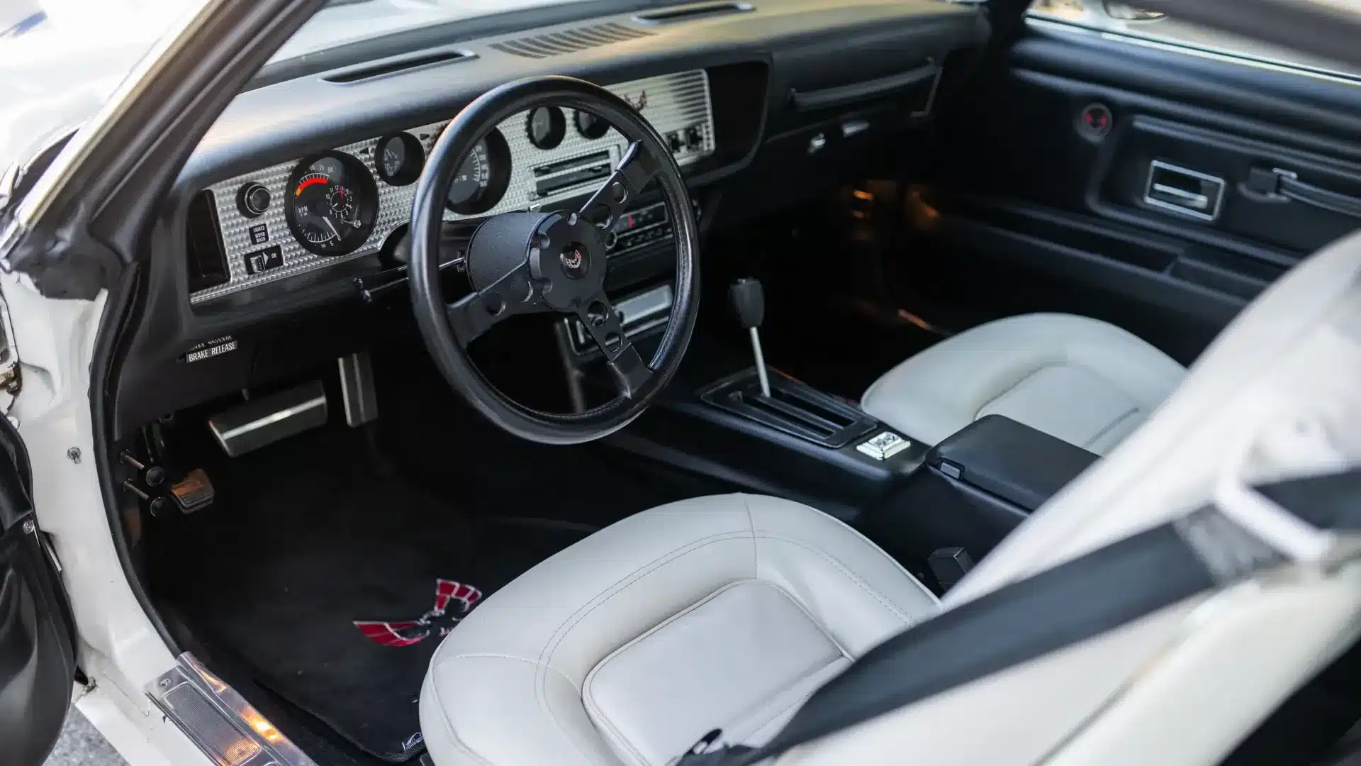 Blick auf das Cockpit eines 1974 Pontiac Trans Am SD-455 mit weißem Vinyl-Interieur und typischem Sportlenkrad.