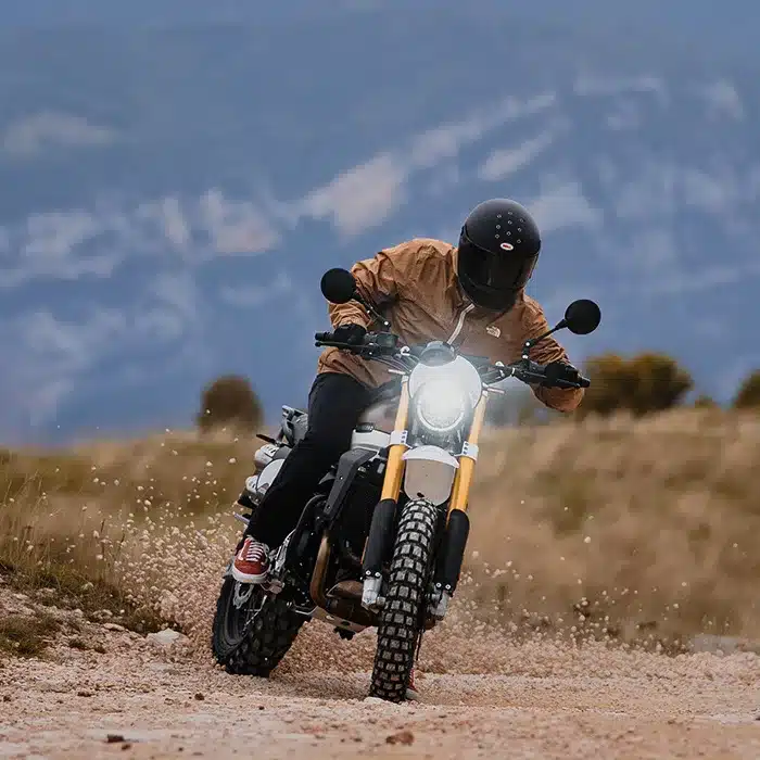 Fahrer auf einer Fantic Caballero 500 Scrambler fährt abseits der Straße über eine Schotterpiste.