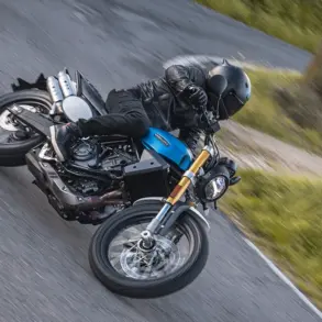 Fantic Caballero 700 Motorrad in blauer Lackierung wird von einem Fahrer sportlich in Schräglage auf einer Landstraße gefahren.