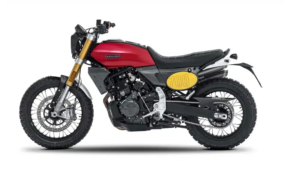 Fantic Caballero 700 Scrambler-Motorrad in Seitenansicht, rote Lackierung, gelbe Nummerntafeln, modernes und klassisches Design kombiniert.