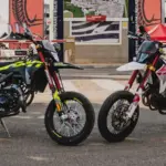 Fantic XM 50 Competition und XMF 125 Competition 2025 nebeneinander vor Messekulisse