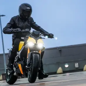 Fahrer mit Schutzkleidung fährt eine Fantic Stealth 125 in gelber Lackierung auf feuchtem Beton