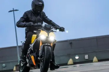 Fahrer mit Schutzkleidung fährt eine Fantic Stealth 125 in gelber Lackierung auf feuchtem Beton