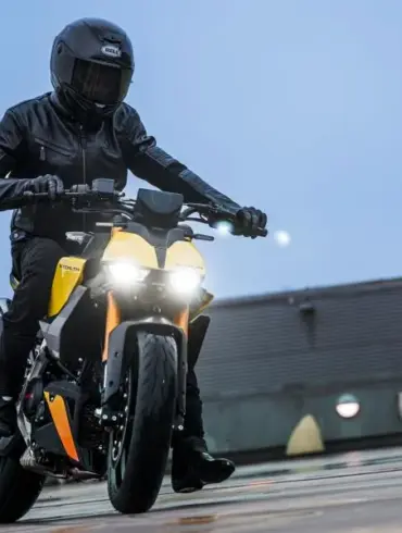 Fahrer mit Schutzkleidung fährt eine Fantic Stealth 125 in gelber Lackierung auf feuchtem Beton