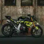 Seitenansicht der Fantic Stealth 125 in Acid Green vor einer Industrie-Mauer