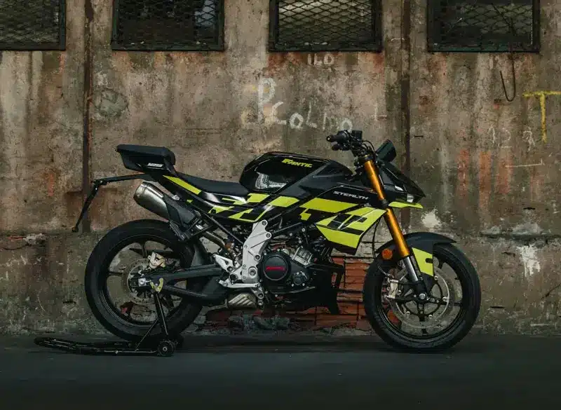 Seitenansicht der Fantic Stealth 125 in Acid Green vor einer Industrie-Mauer