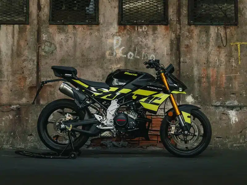 Seitenansicht der Fantic Stealth 125 in Acid Green vor einer Industrie-Mauer