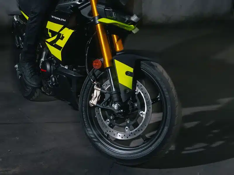 Detailfoto des Vorderrads der Fantic Stealth 125 Acid Green mit Upside-down-Gabel und großen Scheibenbremsen.