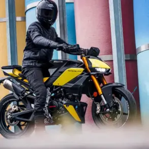 Fantic Stealth 125 Motorrad in Gelb, seitlich fotografiert, Fahrer mit kompletter Schutzkleidung, urbane Kulisse mit bunten Säulen.