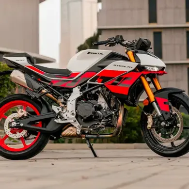 Fantic Stealth 500 Racing White Motorrad in Racing White mit roten Details, seitlich fotografiert vor moderner Kulisse.