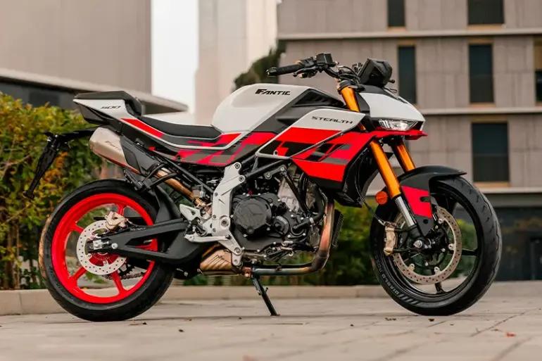 Fantic Stealth 500 Racing White Motorrad in Racing White mit roten Details, seitlich fotografiert vor moderner Kulisse.