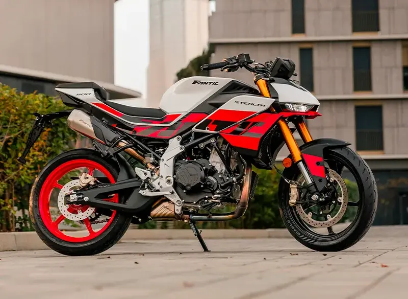 Fantic Stealth 500 Racing White Motorrad in Racing White mit roten Details, seitlich fotografiert vor moderner Kulisse.