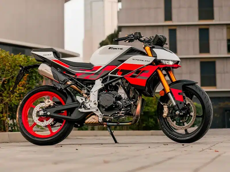 Fantic Stealth 500 Racing White Motorrad in Racing White mit roten Details, seitlich fotografiert vor moderner Kulisse.