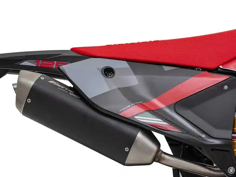 Detailansicht des Arrow-Auspuffs und der Seitenverkleidung der Fantic XEF 125 Competition mit rotem Sitz.