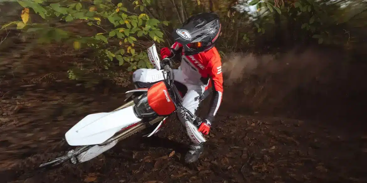 Fantic XEF 310 Enduro-Motorrad fährt durch bewaldetes Gelände, gesteuert von einem Fahrer in roter Ausrüstung.
