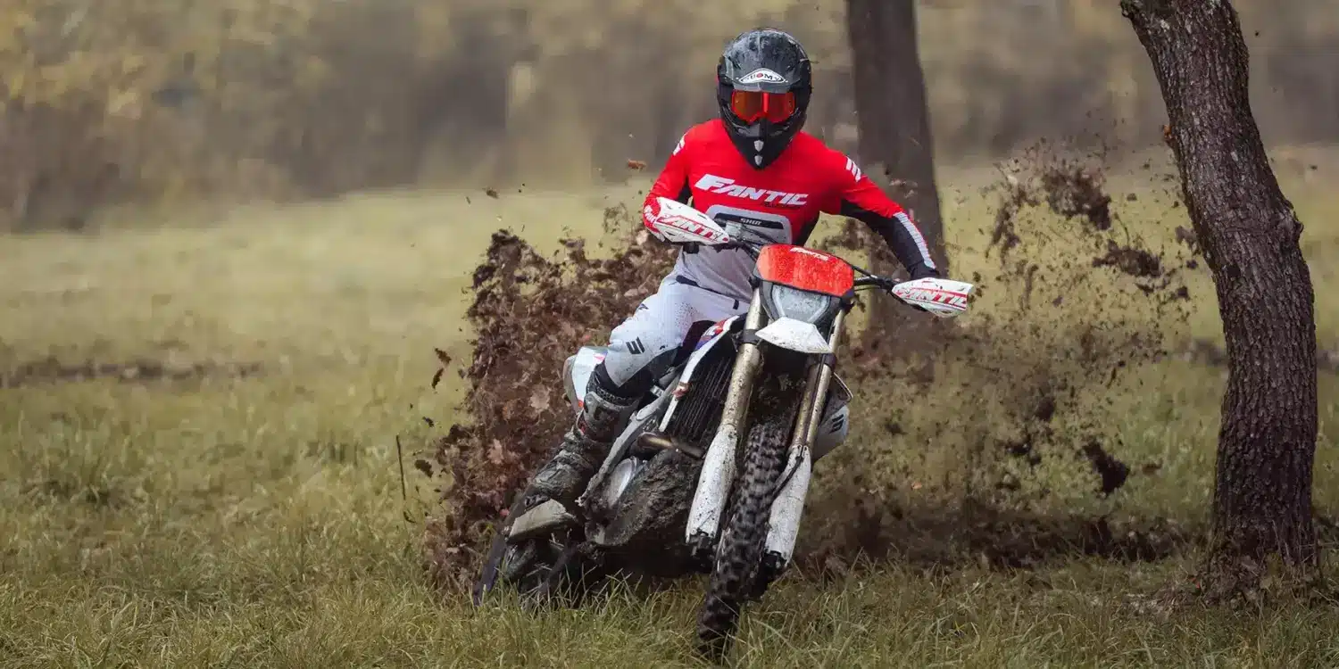 Ein Fahrer bewegt die Fantic XEF 450 durch schlammiges Gelände, spritzt Erde auf und demonstriert die Offroad-Fähigkeiten des Motorrads.