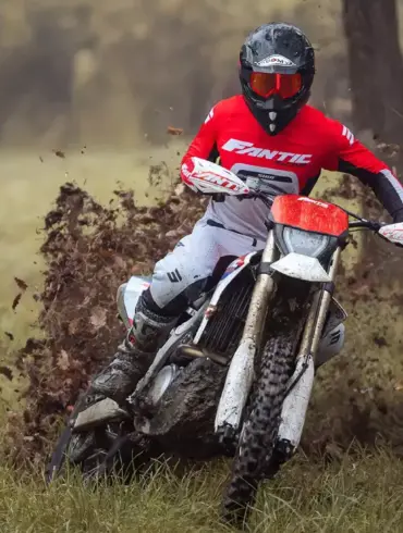 Ein Fahrer bewegt die Fantic XEF 450 durch schlammiges Gelände, spritzt Erde auf und demonstriert die Offroad-Fähigkeiten des Motorrads.