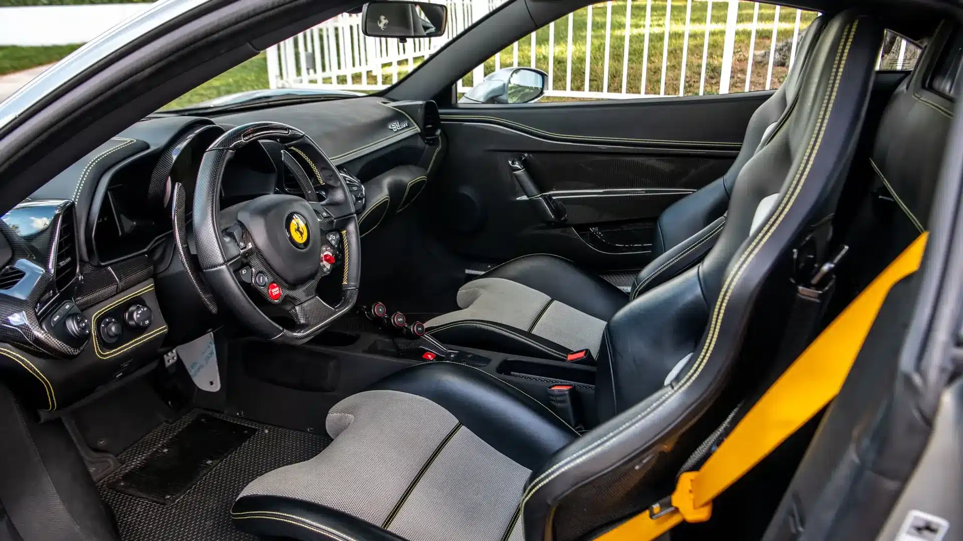 Innenraum eines Ferrari 458 Speciale mit Sportsitzen, gelben Nähten und Carbon-Elementen.