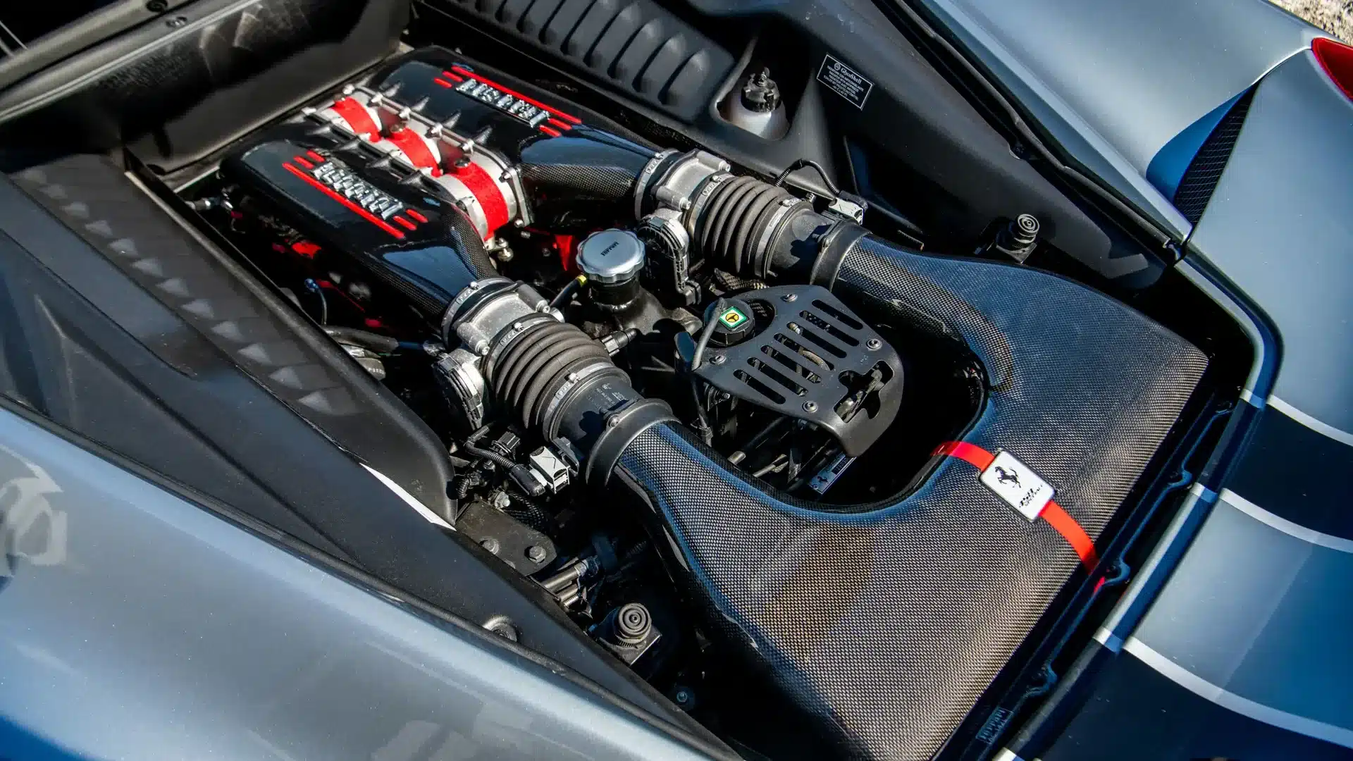 Ferrari 458 Speciale V8-Motor mit sichtbaren Karbonbauteilen und markanten roten Abdeckungen.