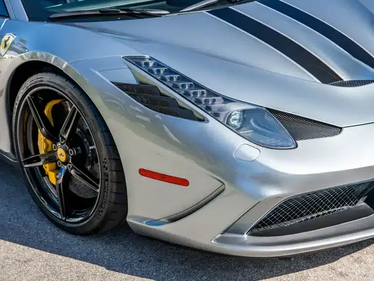 Frontansicht eines silbernen Ferrari 458 Speciale mit dunklen Streifen, gelben Bremssätteln und sichtbaren Karbon-Elementen.