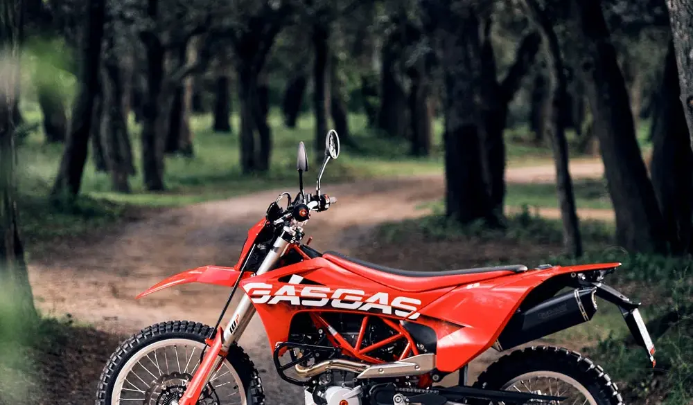 Rote GASGAS ES 700 Enduro stehend auf einem Waldweg, seitliche Ansicht.