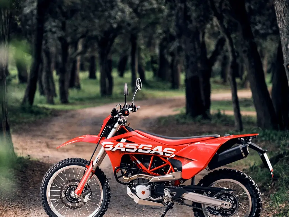 Rote GASGAS ES 700 Enduro stehend auf einem Waldweg, seitliche Ansicht.