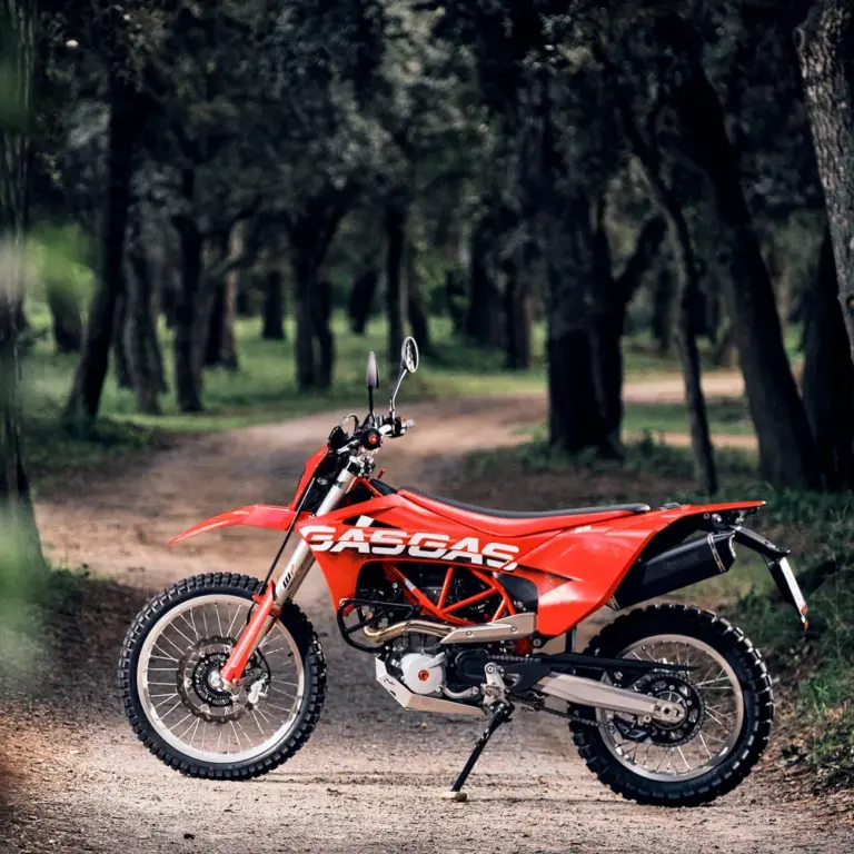 Rote GASGAS ES 700 Enduro stehend auf einem Waldweg, seitliche Ansicht.