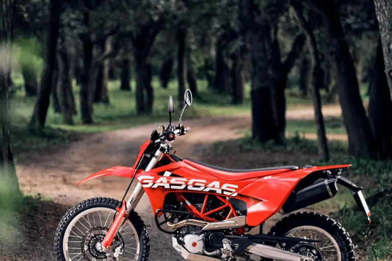 Rote GASGAS ES 700 Enduro stehend auf einem Waldweg, seitliche Ansicht.