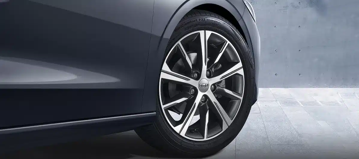 Nahaufnahme des 17-Zoll-Leichtmetallrads am Geely Emgrand vor einer Betonwand