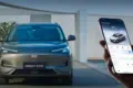 Frontansicht des elektrischen SUVs Geely EX5, daneben ein Smartphone mit Fahrzeug-App.