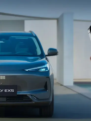 Frontansicht des elektrischen SUVs Geely EX5, daneben ein Smartphone mit Fahrzeug-App.