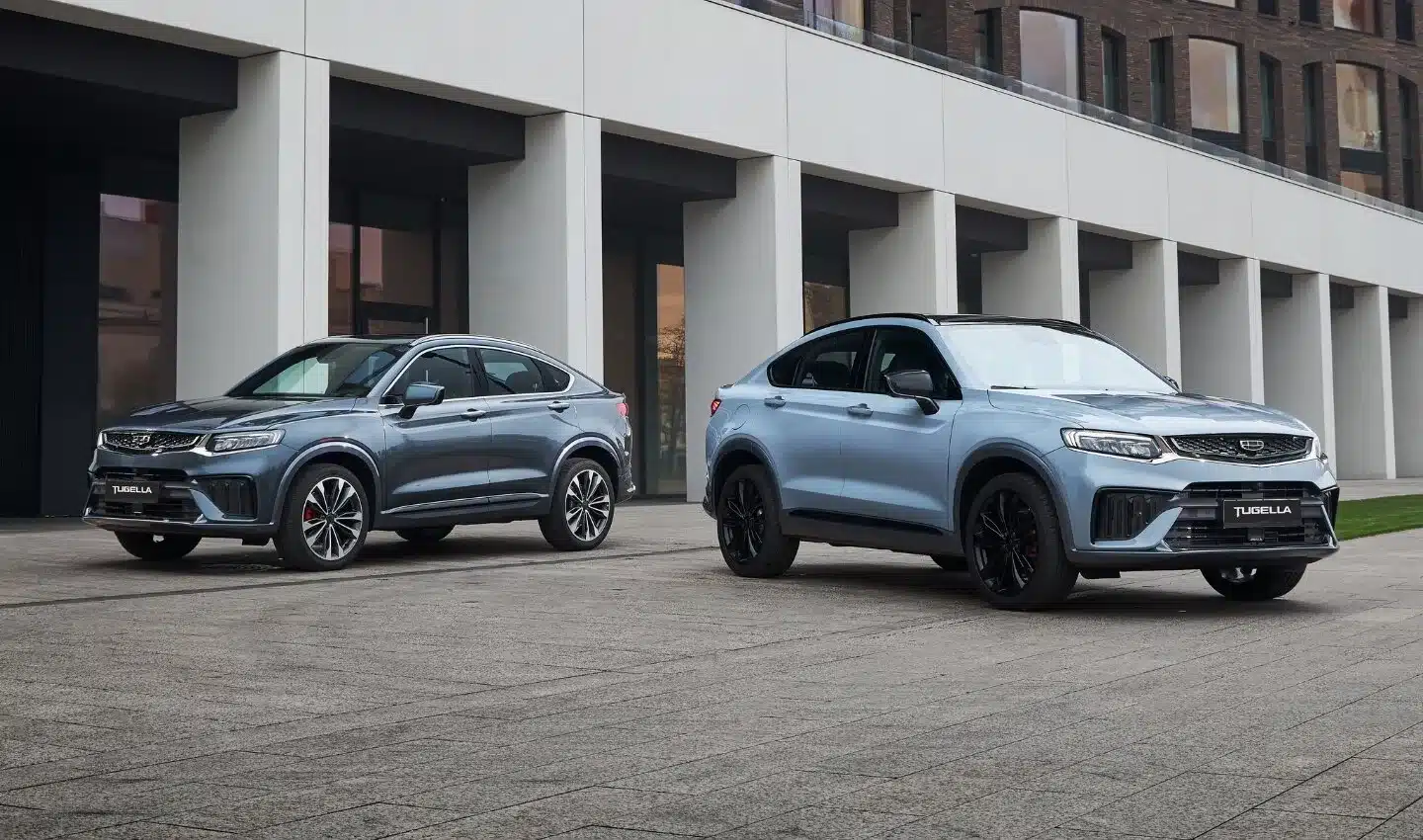 Zwei Geely Tugella SUV nebeneinander vor einem modernen Gebäude
