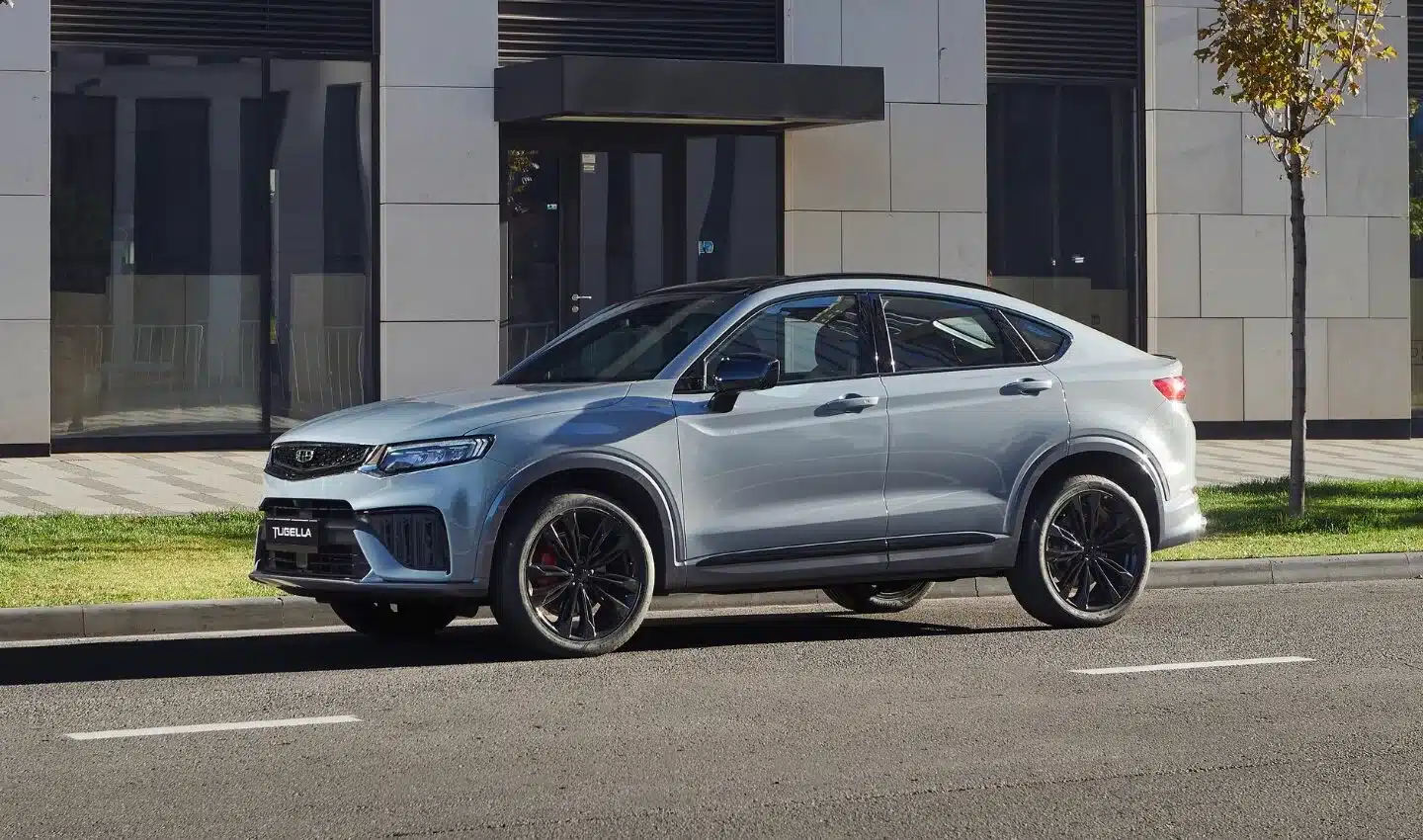 Seitenansicht des Geely Tugella SUV in Silber vor einem modernen Gebäude