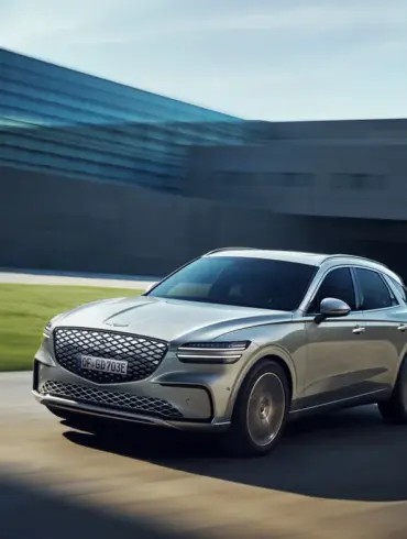 Genesis Electrified GV70 fährt dynamisch vor moderner Kulisse.