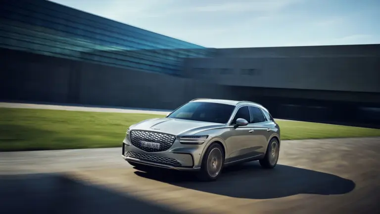 Genesis Electrified GV70 fährt dynamisch vor moderner Kulisse.