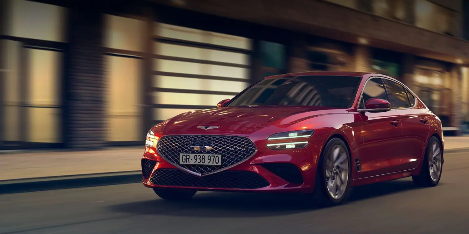 Genesis G70 in Rot, fahrend auf einer nächtlichen Straße vor Gebäuden