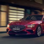 Genesis G70 in Rot, fahrend auf einer nächtlichen Straße vor Gebäuden