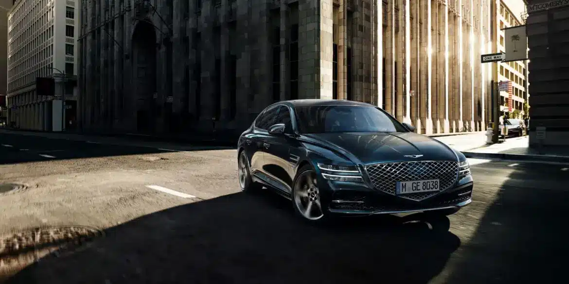 Genesis G80 Limousine fährt auf einer sonnigen Straße in der Stadt, frontal aufgenommen